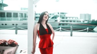 girl in a red dress near the colorful flowers at the river station