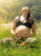 happy Pregnant Woman sitting on summer meadow