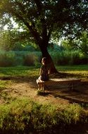 girl is sitting on a wooden bench in the park