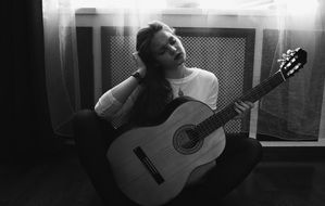 black and white photo of a girl with a guitar in her hands