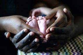baby feet in the hands of a man and a woman