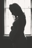 silhouette of a pregnant girl near the window