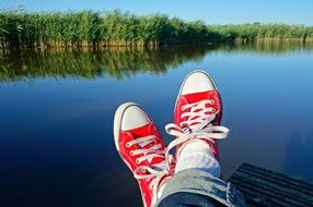 legs in red sneakers on the background of the lake