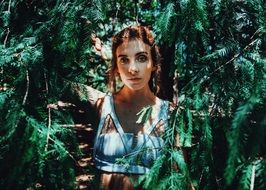 Pretty young red haired girl among greenery