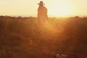 girl in a straw hat in countryside at sunset
