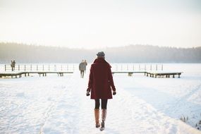 girl in a coat goes to the pier in winter