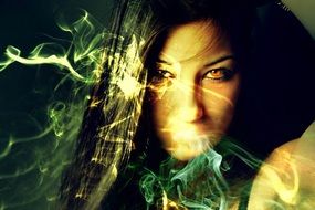 Sorceress, face of dark haired woman behind colorful smoke, collage