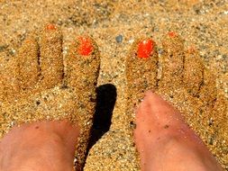 orange manicure and yellow sand on the feet