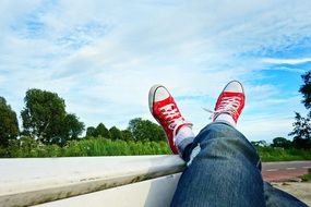 legs in denim pants and red sneakers