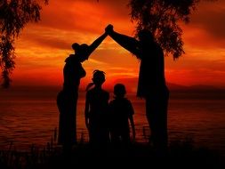 family silhouette on sunset sky background