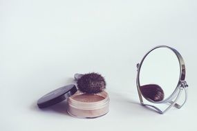 powder, mirror and brush on the table
