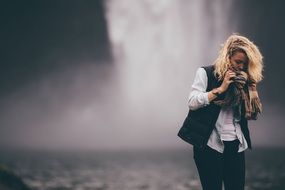 woman with blond hair near a waterfall