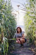 Young Girl sits on path among reed at Lake