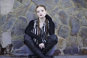 girl sitting near a stone wall