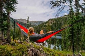 girl lies in a hammock near the lake