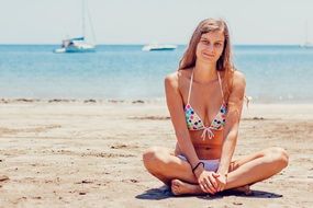 girl in a bathing suit sitting on the beach