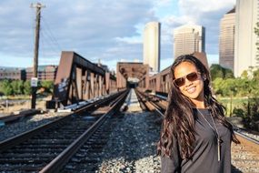 beautiful young woman with the sunglasses on the railway on a sunny day