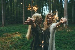 two joyful Girls with Sparklers in hands in forest