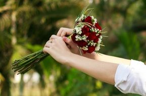 red-white wedding bouquet of flowers in hand