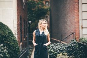 blonde in a black dress on the background of urban houses