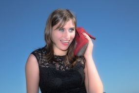 Glamour model girl with red shoe in her hand