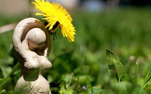 small goddess stone statue in a green grass meadow