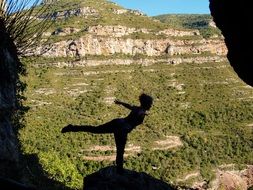 silhouette of a girl in a yoga pose in the mountains