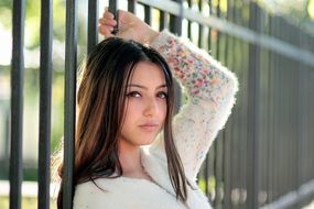 girl with long hair posing near the fence