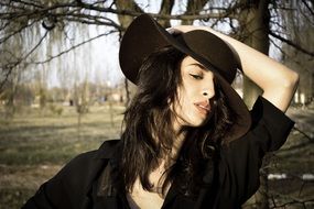 girl in a big black hat among the plants