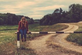 girl sitting on a road barrier