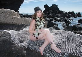 sexy caucasian girl sits on rock at sea