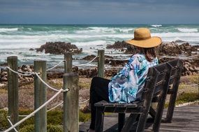 woman sitting on a bench on the coast