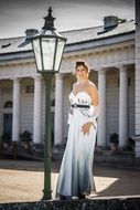 young woman in a long white dress near a street lamp