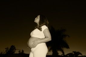 Pregnant woman is looking on the sky