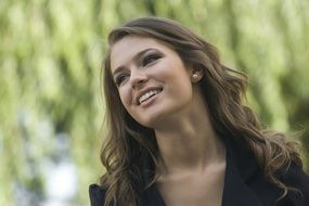 smiling girl with long hair on the background of a tree