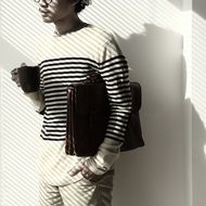 young man in a striped sweater with a case and a cup of coffee