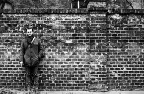 black and white photo of a man against a brick wall