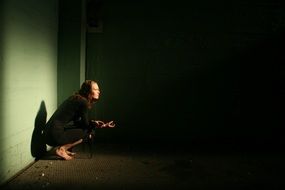 girl squatting in a dark room