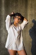 girl stands in a white shirt near the wall