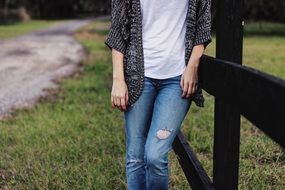 woman stands near a wooden fence