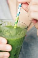 green vegetable juice in a glass with a straw