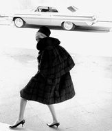 retro photo model in a fur coat on the background of the car