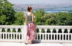 girl looks into the distance standing at the railing
