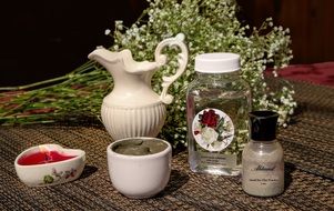 jug, masks, candles and water from roses on the table