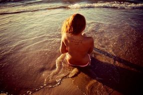 naked girl with a tattoo on the seashore