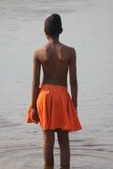 girl in an orange skirt near the water