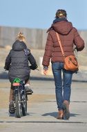 girl on a bicycle and mom walk in the park