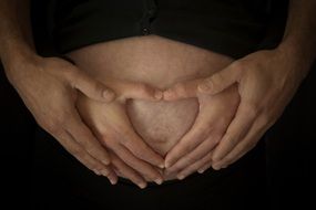 hands of man and woman on a pregnant belly