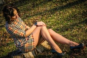 girl in a striped dress sits on a tree trunk