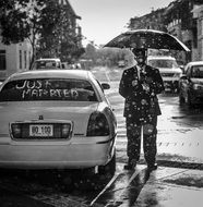 black and white photo driver with an umbrella at a wedding limousine